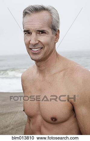 Stock Image - Caucasian man standing on beach. Fotosearch