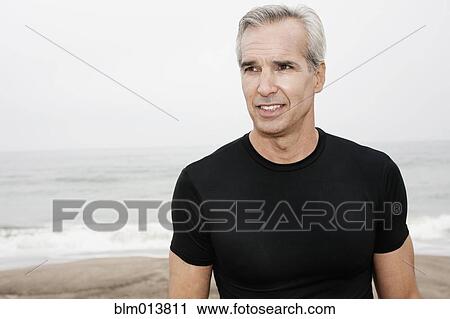 Stock Image - Caucasian man standing on beach. Fotosearch