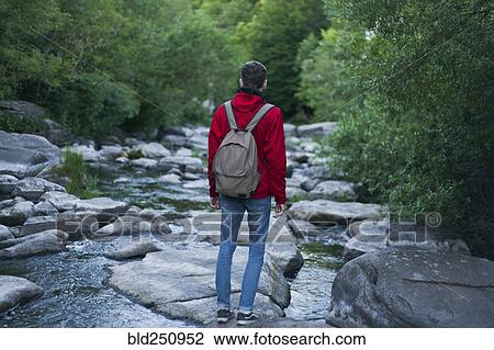 Stock Image - Caucasian man standing on rock in river. Fotosearch