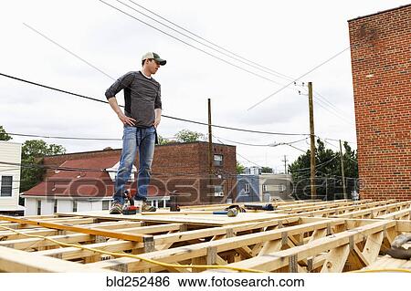 Caucasian man standing on the roof construction site View Large Photo Image Stock Photograph - Caucasian man standing on the roof construction site. Fotosearch