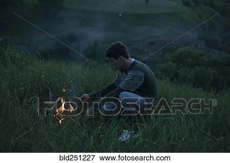 Caucasian man starting campfire at night View Large Photo Image Stock Photo - Caucasian man starting campfire at night. Fotosearch
