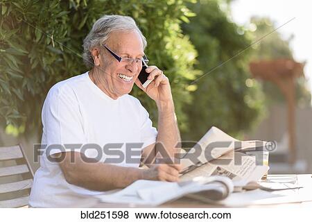 Caucasian man talking on cell phone and reading newspaper View Large Photo Image Stock Photo - Caucasian man talking on cell phone and reading newspaper. Fotosearch