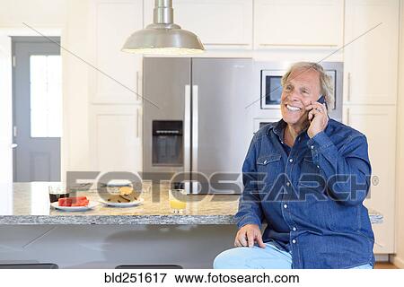 Caucasian man talking on cell phone in kitchen View Large Photo Image Stock Photo - Caucasian man talking on cell phone in kitchen. Fotosearch