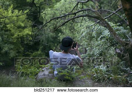 Caucasian man texting on cell phone in woods View Large Photo Image Stock Photo - Caucasian man texting on cell phone in woods. Fotosearch