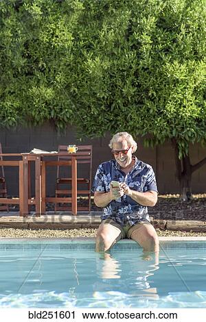 Caucasian man texting on cell phone with legs in swimming pool View Large Photo Image Stock Image - Caucasian man texting on cell phone with legs in swimming pool. Fotosearch