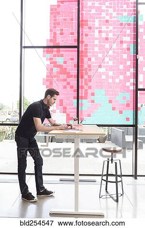 Caucasian man using a laptop at standing workstation View Large Photo Image Stock Photo - Caucasian man using a laptop at standing workstation. Fotosearch