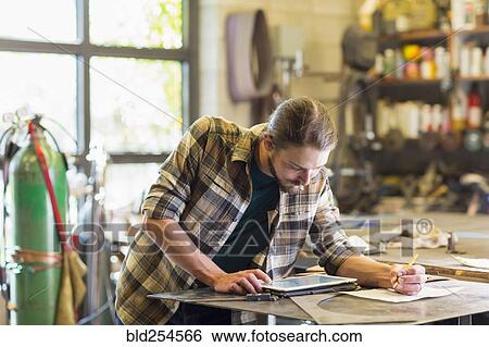 Stock Photograph - Caucasian man using digital tablet in workshop. Fotosearch