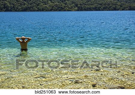 Stock Image - Caucasian man wading in water. Fotosearch