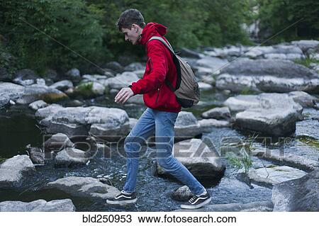 Caucasian man walking on rocks crossing river View Large Photo Image Stock Image - Caucasian man walking on rocks crossing river. Fotosearch