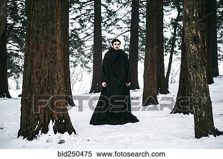 Stock Photography - Caucasian man with beard wearing robe in forest during winter. Fotosearch