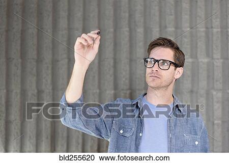 Stock Image - Caucasian man writing on glass wall. Fotosearch