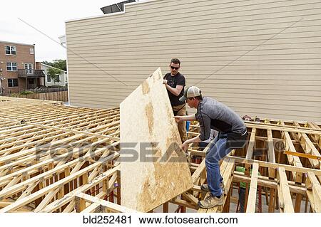Caucasian men carrying plywood at construction site View Large Photo Image Stock Image - Caucasian men carrying plywood at construction site. Fotosearch