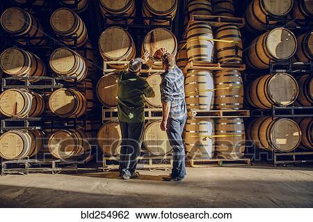 Caucasian men examining barrel in distillery View Large Photo Image Stock Image - Caucasian men examining barrel in distillery. Fotosearch