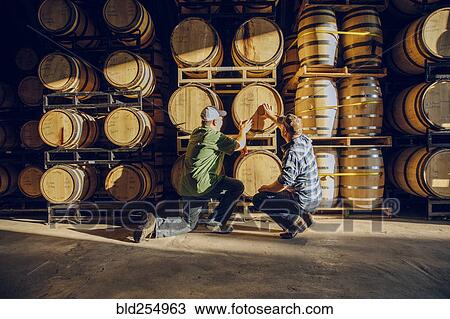 Caucasian men examining barrel in distillery View Large Photo Image Stock Image - Caucasian men examining barrel in distillery. Fotosearch