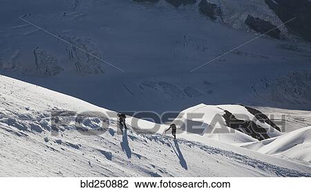 Stock Image - Caucasian men hiking on mountain in winter. Fotosearch
