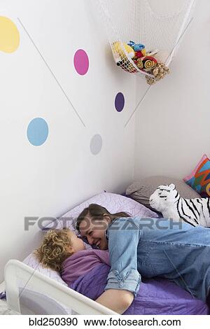Caucasian mother and daughter laughing and cuddling in bed View Large Photo Image Stock Image - Caucasian mother and daughter laughing and cuddling in bed. Fotosearch