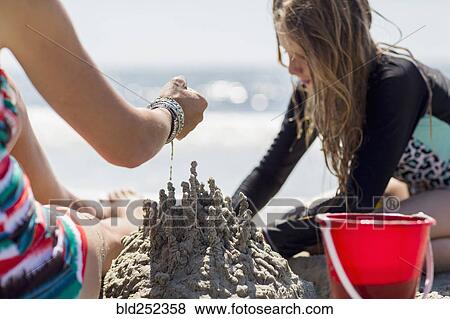 Caucasian mother and daughter playing with sand castle at the beach View Large Photo Image Stock Photo - Caucasian mother and daughter playing with sand castle at the beach. Fotosearch
