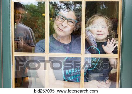 Stock Photography - Caucasian mother and son making a face in door window. Fotosearch