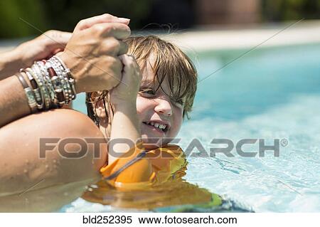 Stock Photography - Caucasian mother holding hands of swimming boy. Fotosearch