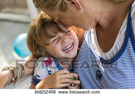 Stock Photograph - Caucasian mother hugging laughing son holding toy car. Fotosearch