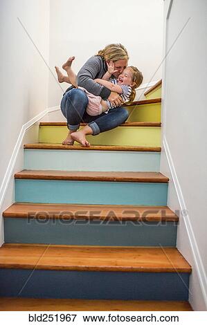 Stock Photo - Caucasian mother kissing daughter on staircase. Fotosearch