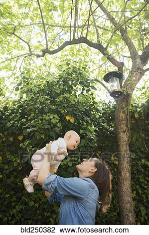 Caucasian mother lifting baby daughter under tree View Large Photo Image Stock Image - Caucasian mother lifting baby daughter under tree. Fotosearch