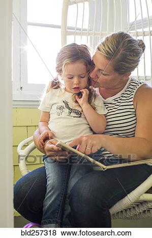 Caucasian mother reading book to daughter on lap View Large Photo Image Stock Photo - Caucasian mother reading book to daughter on lap. Fotosearch