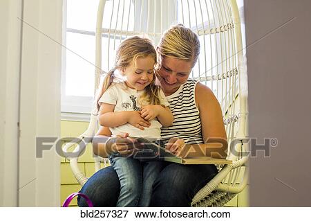 Caucasian mother reading book to daughter on lap View Large Photo Image Stock Photo - Caucasian mother reading book to daughter on lap. Fotosearch