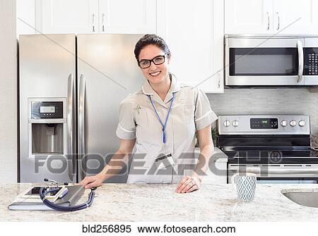 Stock Photography - Caucasian nurse posing in kitchen. Fotosearch