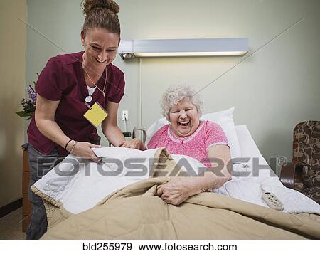 Stock Photo - Caucasian nurse with laughing patient in hospital bed. Fotosearch