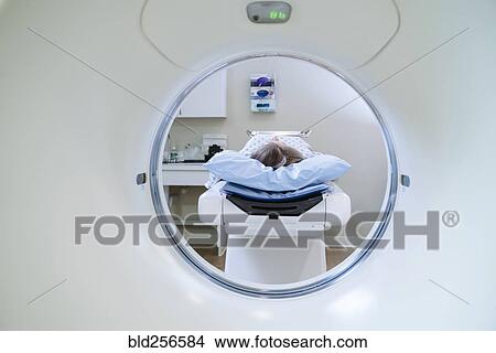 Picture - Caucasian patient laying on scanner table. Fotosearch