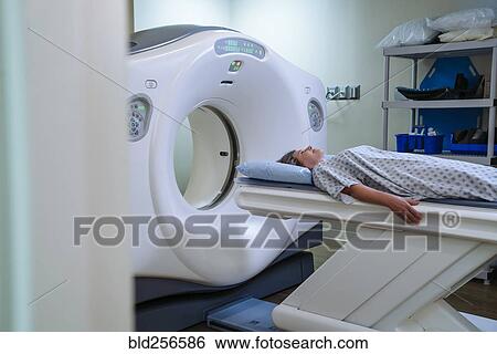 Stock Photograph - Caucasian patient laying on scanner table. Fotosearch