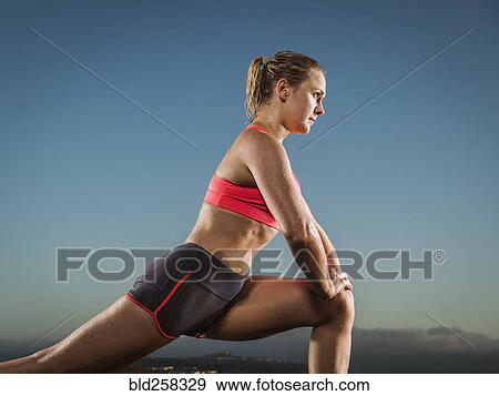 Stock Photo - Caucasian runner stretching legs. Fotosearch
