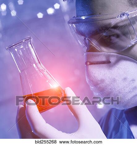 Stock Photo - Caucasian scientist examining red liquid. Fotosearch