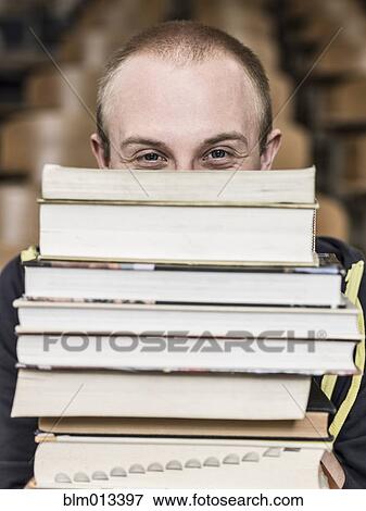Stock Photo - Caucasian student holding stack of books. Fotosearch