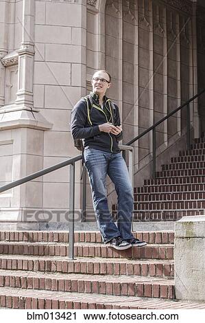 Stock Image - Caucasian student standing on campus staircase. Fotosearch