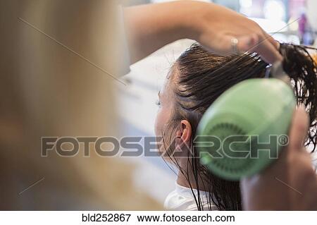 Stock Photo - Caucasian stylist drying hair of woman. Fotosearch