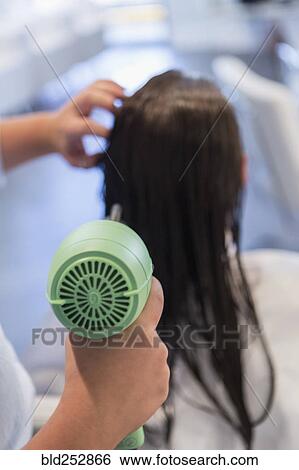 Stock Photograph - Caucasian stylist drying hair of woman. Fotosearch