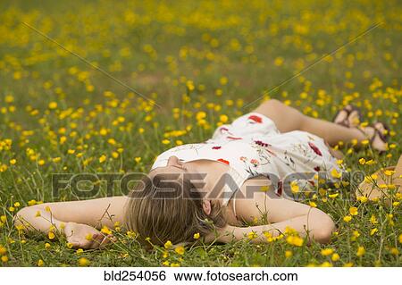 Stock Photograph - Caucasian teenage girl laying in field of flowers. Fotosearch
