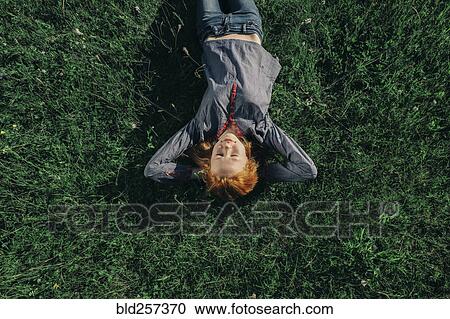 Stock Image - Caucasian teenage girl laying in grass. Fotosearch