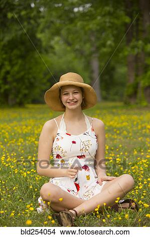 Picture - Caucasian teenage girl sitting in field of flowers. Fotosearch