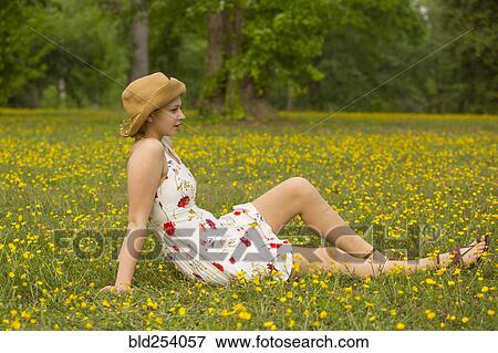 Stock Photo - Caucasian teenage girl sitting in field of flowers. Fotosearch