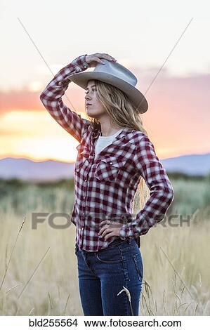 Picture - Caucasian teenage girl wearing cowboy hat at sunset. Fotosearch