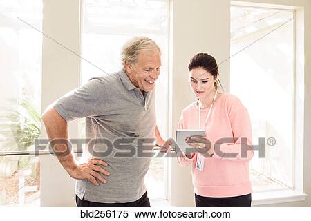Caucasian trainer showing digital tablet to man View Large Photo Image Stock Photography - Caucasian trainer showing digital tablet to man. Fotosearch