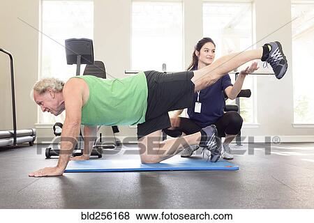Caucasian trainer watching man balance on knee View Large Photo Image Stock Photo - Caucasian trainer watching man balance on knee. Fotosearch