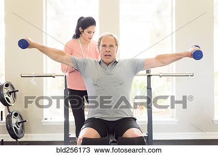 Caucasian trainer watching man lifting dumbbells View Large Photo Image Stock Image - Caucasian trainer watching man lifting dumbbells. Fotosearch