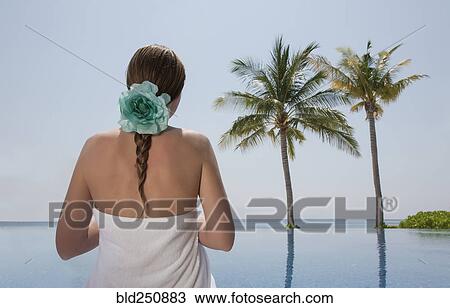 Stock Image - Caucasian woman admiring palm trees near ocean. Fotosearch