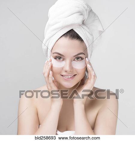 Stock Image - Caucasian woman applying makeup to cheeks. Fotosearch