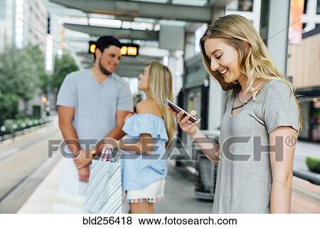 Caucasian woman at train station texting on cell phone View Large Photo Image Stock Photo - Caucasian woman at train station texting on cell phone. Fotosearch