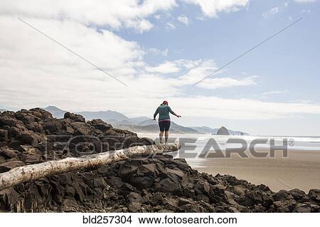 Caucasian woman balancing on log on rocks at beach View Large Photo Image Picture - Caucasian woman balancing on log on rocks at beach. Fotosearch